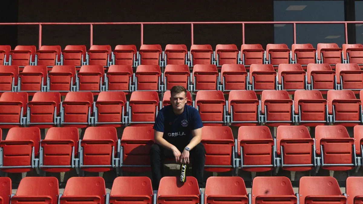 man sat in red seating area holding bottle of grilla