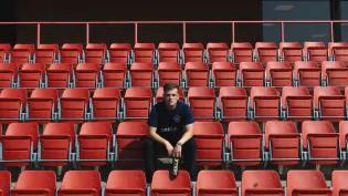 man sat in red seating area holding bottle of grilla