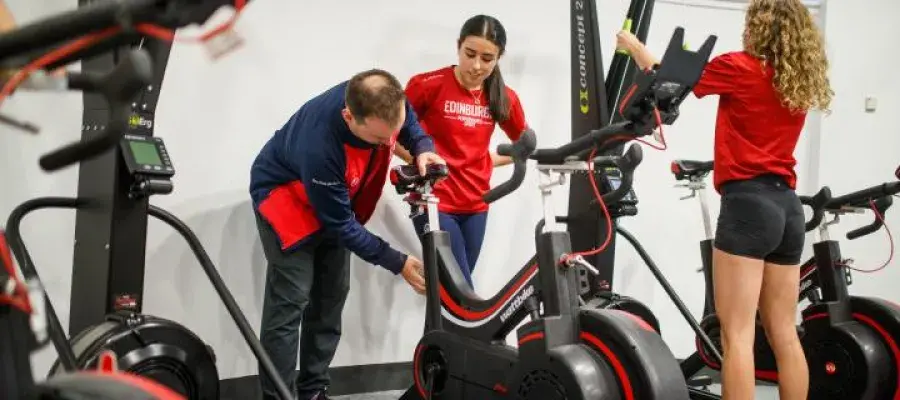 Three people gathered around gym equipment
