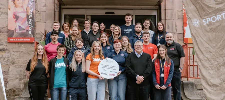 image of group of university of edinburgh staff and students and SAMH staff outside pleasance gym smiling in group photo
