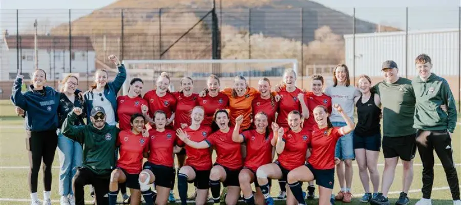 Image of women's football squad on pitch with Arthur's seat in the background