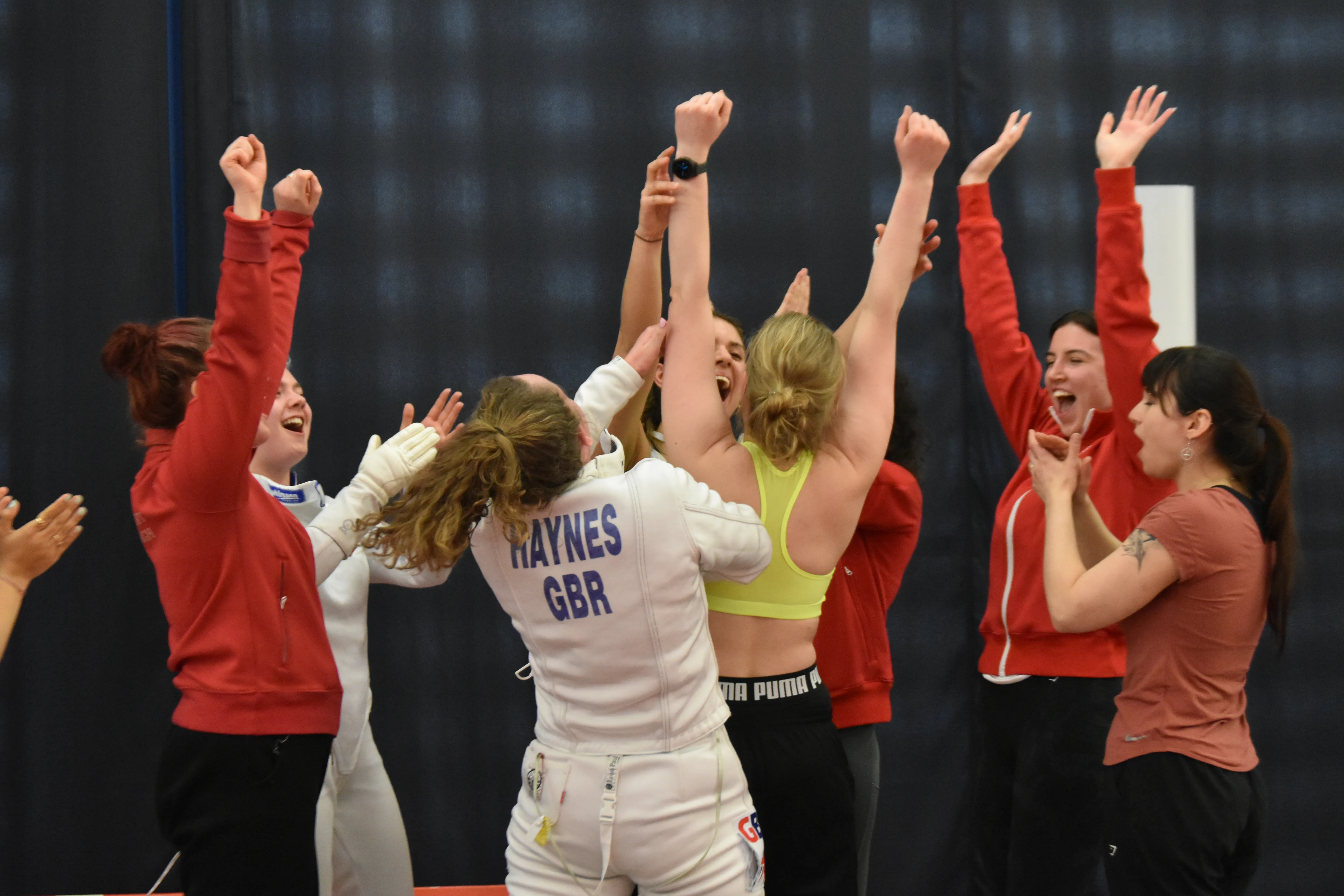 Fencers celebrating together in a huddle