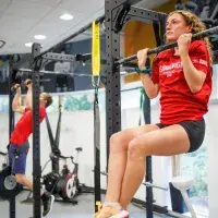 Two gym members doing pull ups in gym