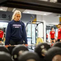 Woman in Edinburgh Cricket jumper poised to lift weight