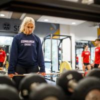 Woman in Edinburgh Cricket jumper poised to lift weight