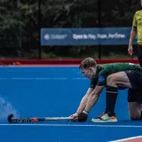 Boy hitting hockey ball on water based pitch