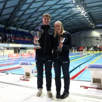 2 people in front of swimming pool with trophies