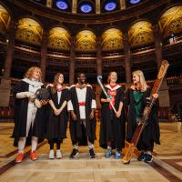 Image of 5 students standing in McEwan Hall in Graduation gowns with university sport kit underneath and equipment