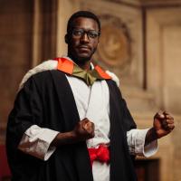 Image of man in graduation robes wearing karate kit in McEwan Hall