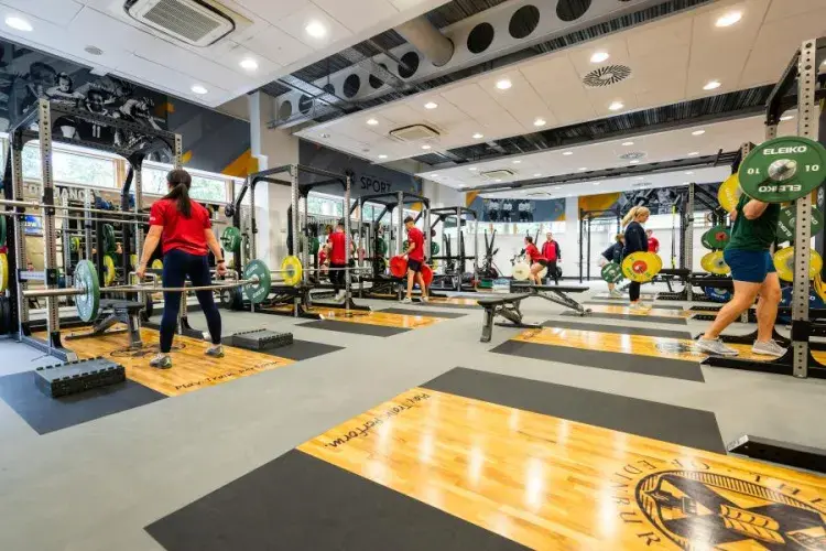 View of gym with members lifting weights in distance