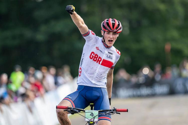 Charlie on bike with one arm in punching the air