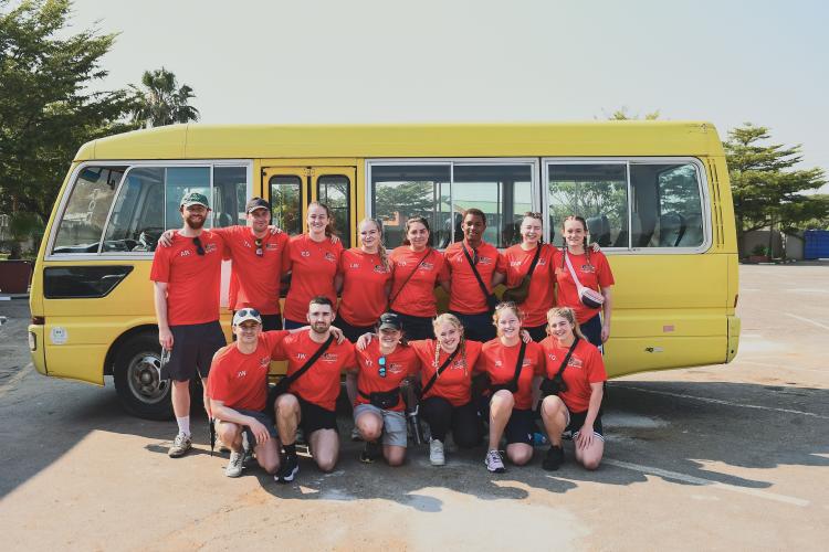 a group of students infront of a yellow bus in Zambia