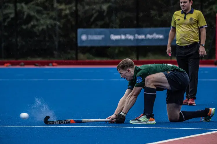 Boy hitting hockey ball on water based pitch