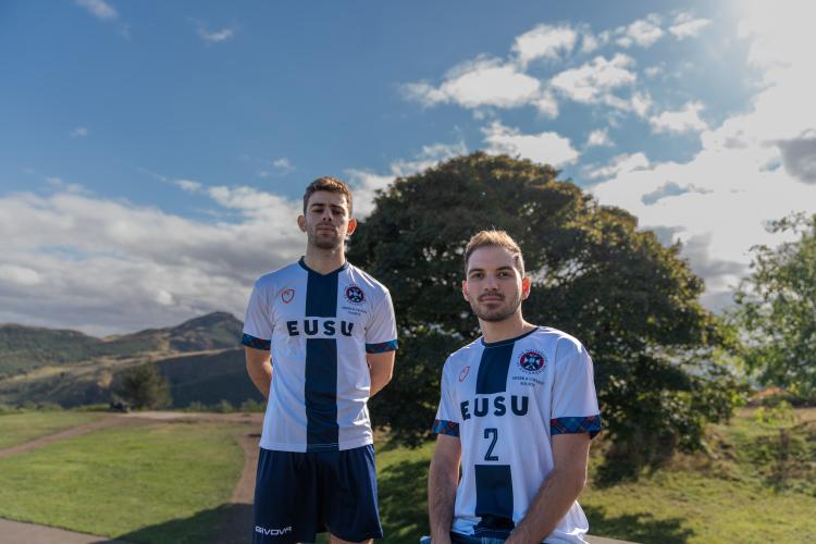 two people in sports kit with view of Edinburgh behind