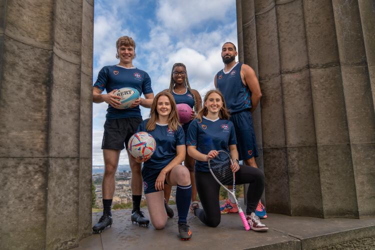 group of 5 people on calton monument holding sports equipment