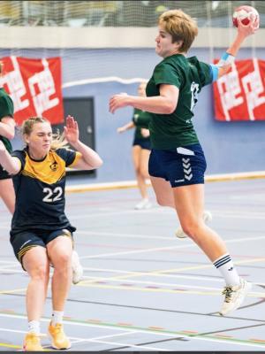 women playing handball, jumping in the air to shoot