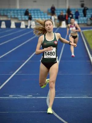 women crossing the finish line on outdoor athletics track