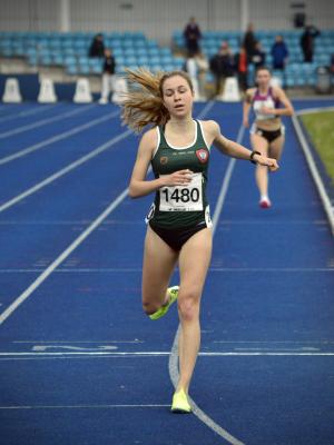 women crossing the finish line on outdoor athletics track