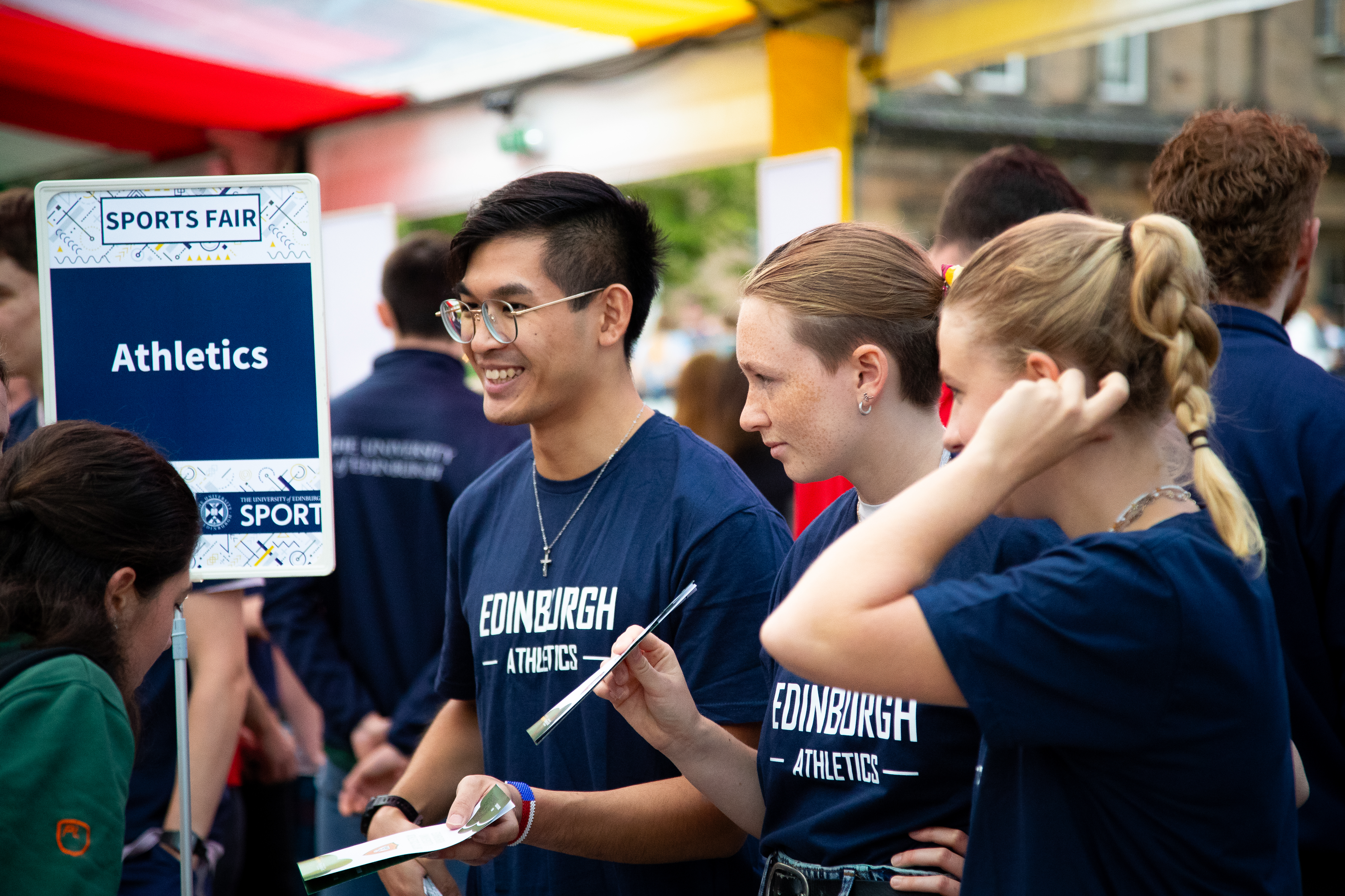 Student athletics club volunteers speaking to new students at sports fair