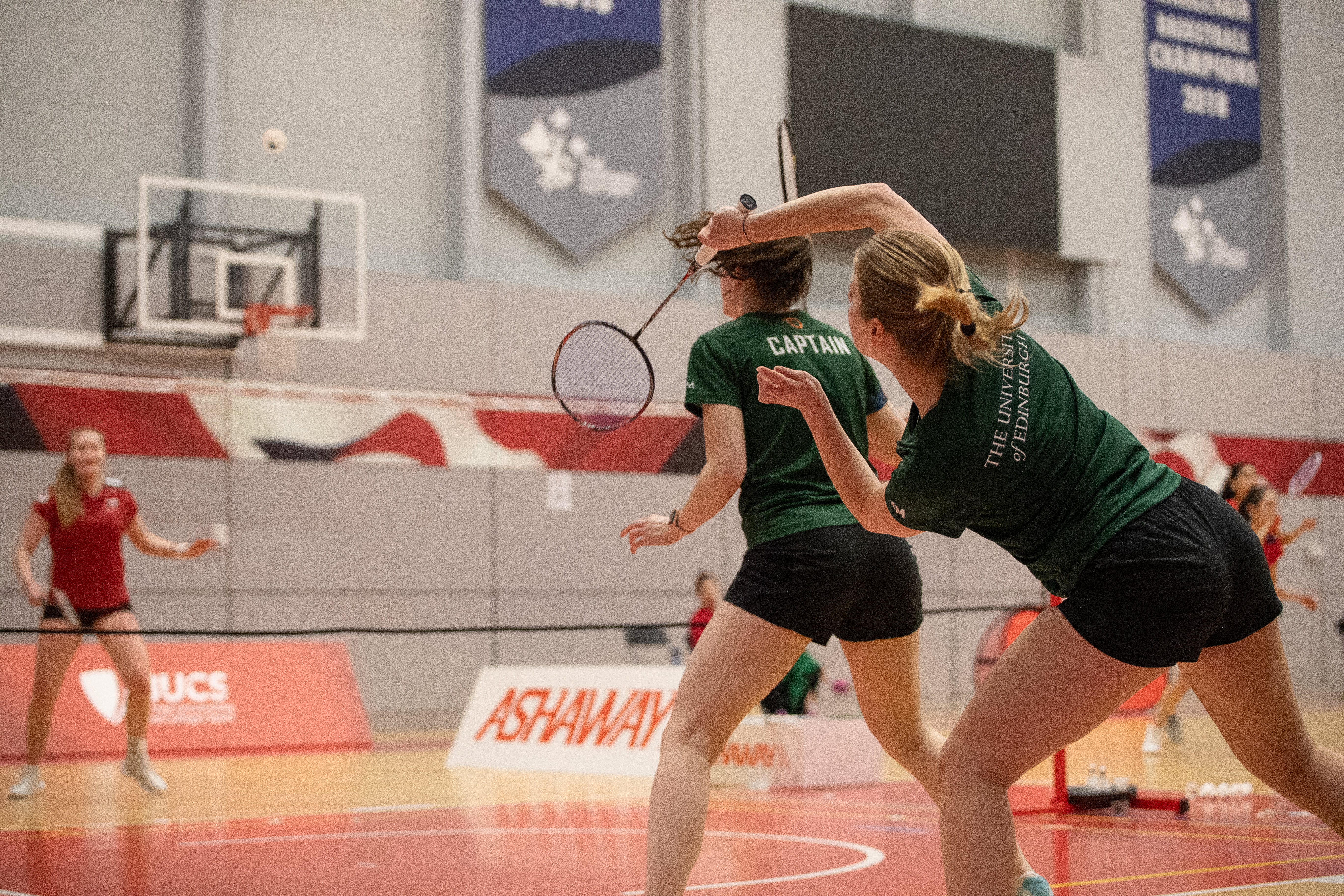 Image of women's doubles playing badminton match