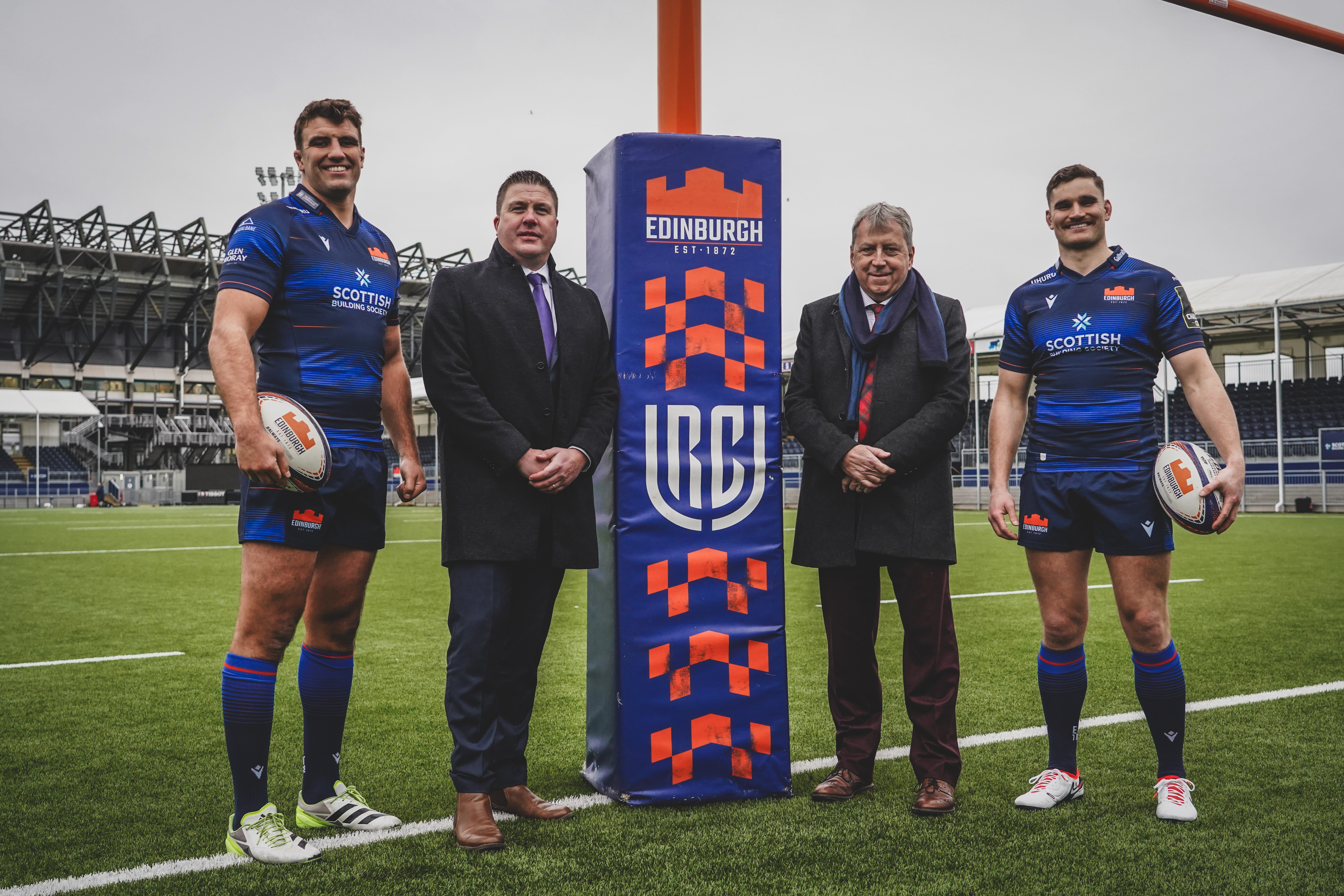 Image of Douglas Struth and Peter Mathison with Edinburgh Rugby players by posts on rugby pitch