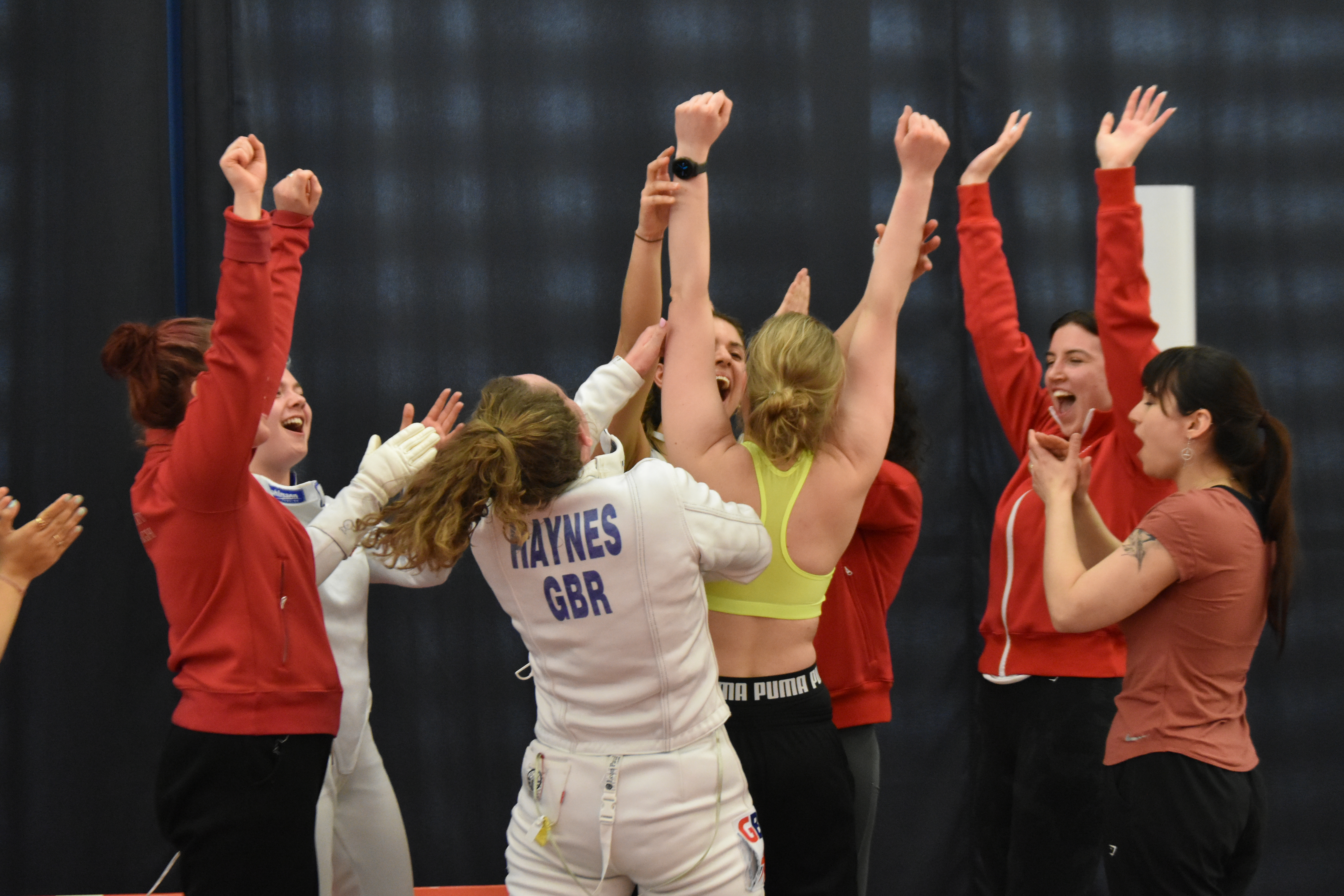 Fencers celebrating together in a huddle