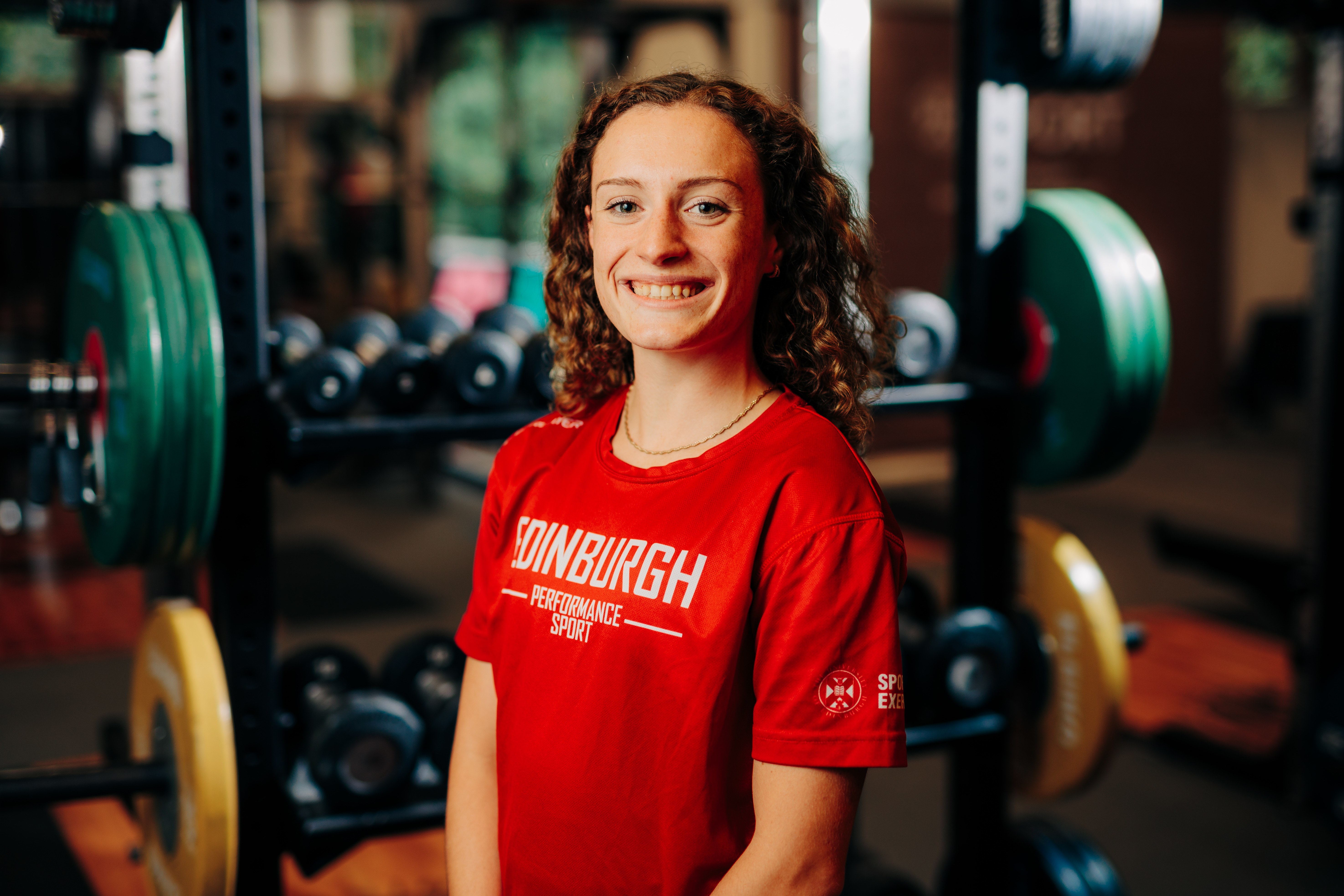 Image of sport scholar Alyson Bell smiling with gym in background