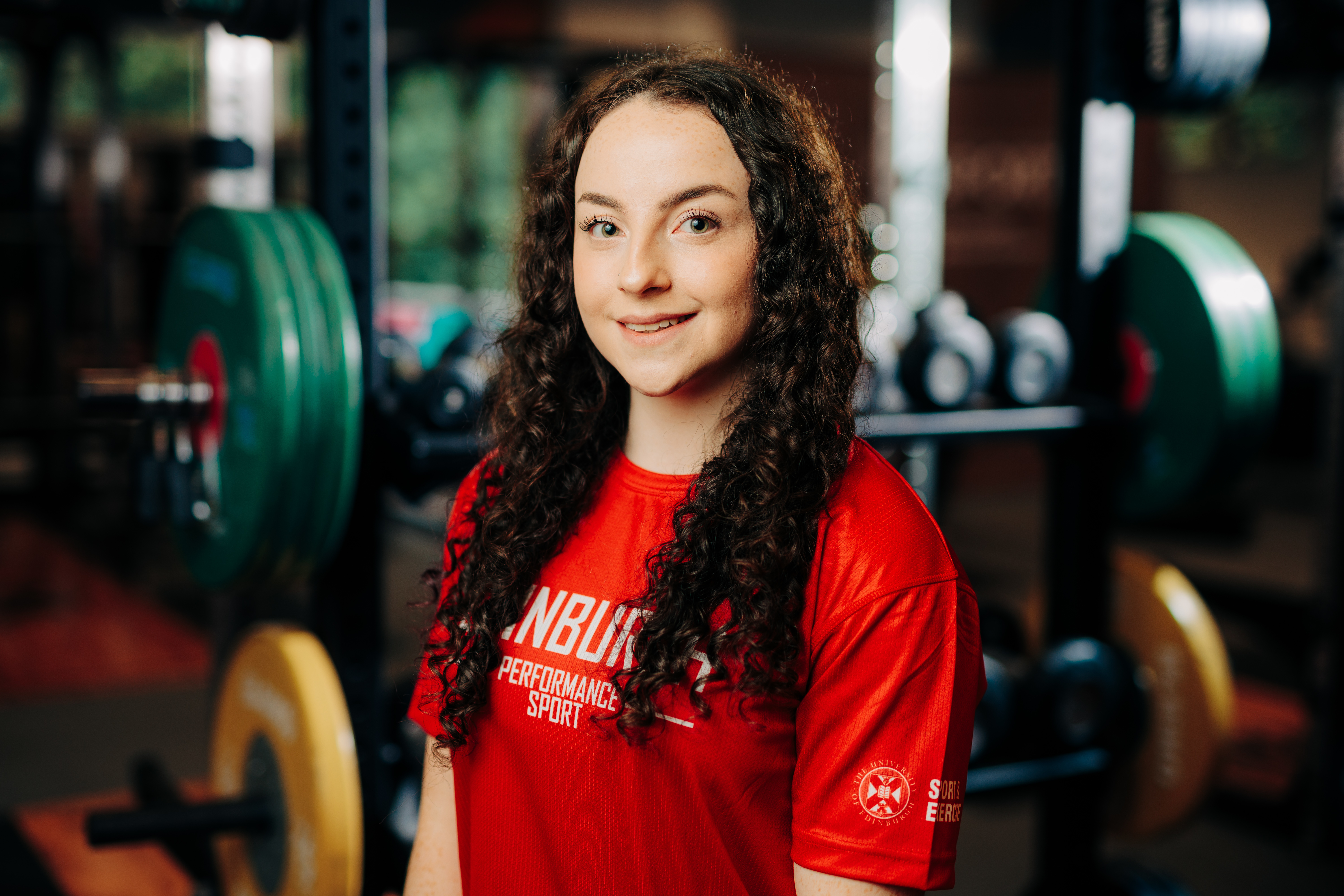 Image of sport scholar Ellie Russell smiling with gym in background