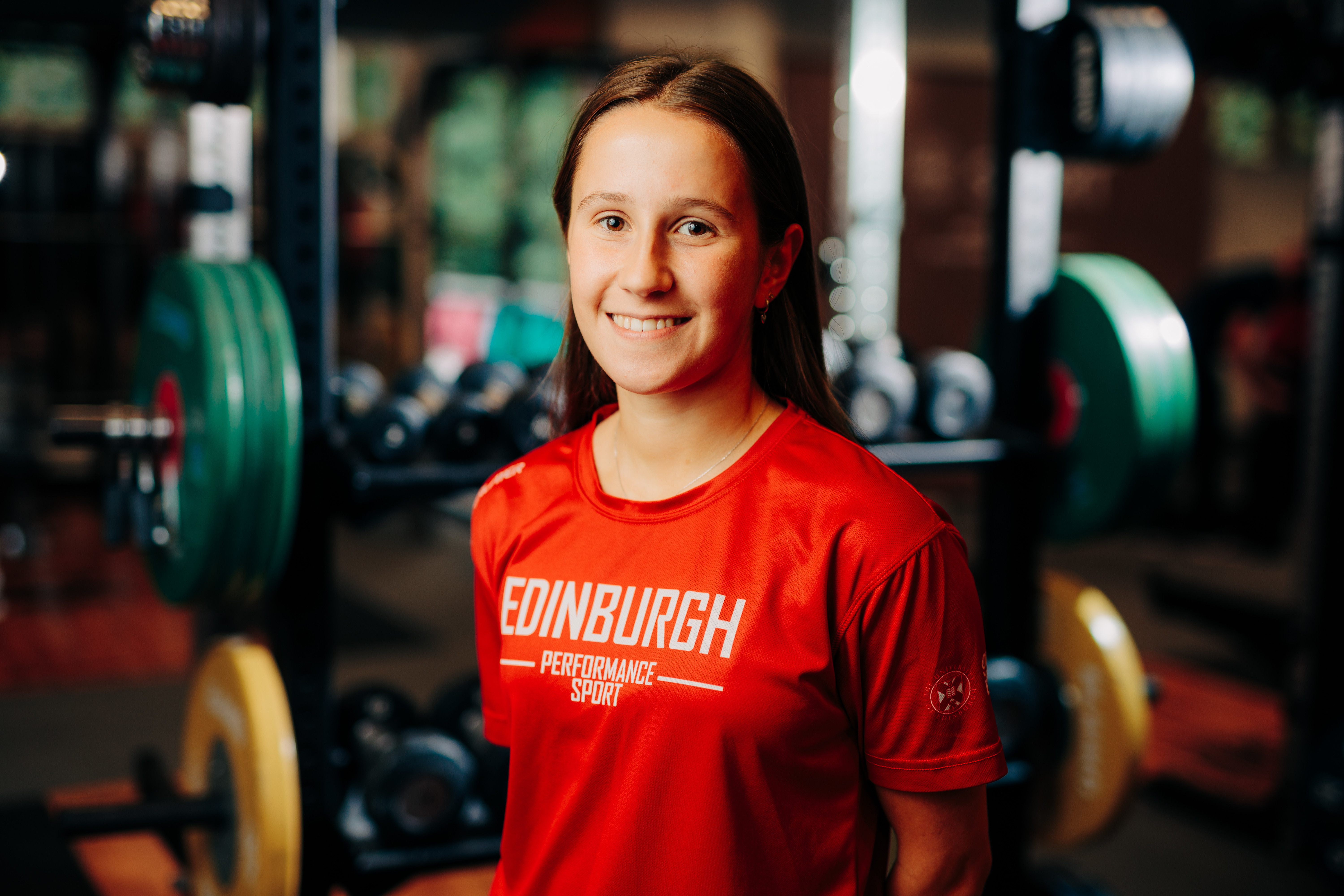 Image of sport scholar Lucy Murchie smiling with gym in background