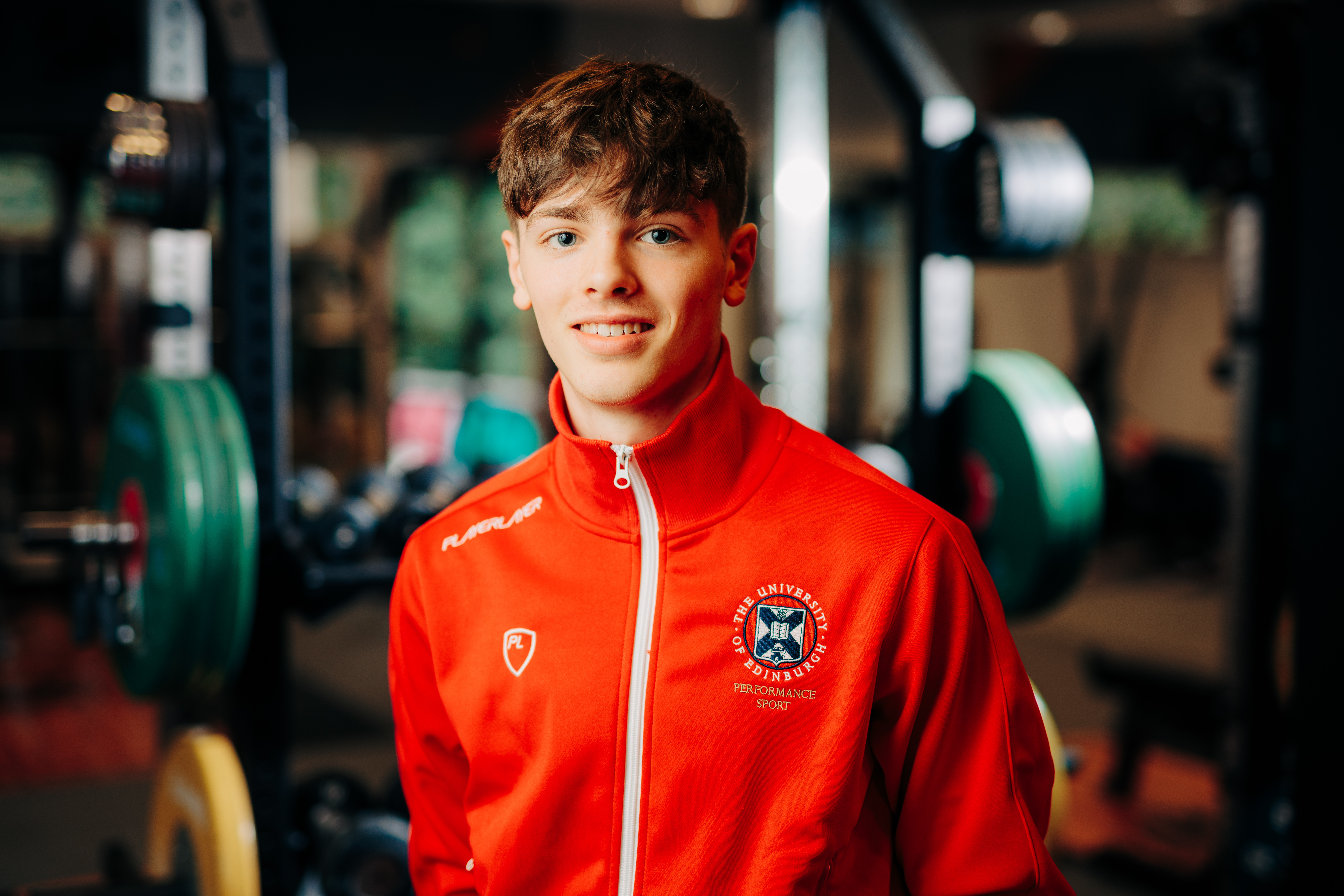Image of sport scholar Adam Hamill smiling with gym in background