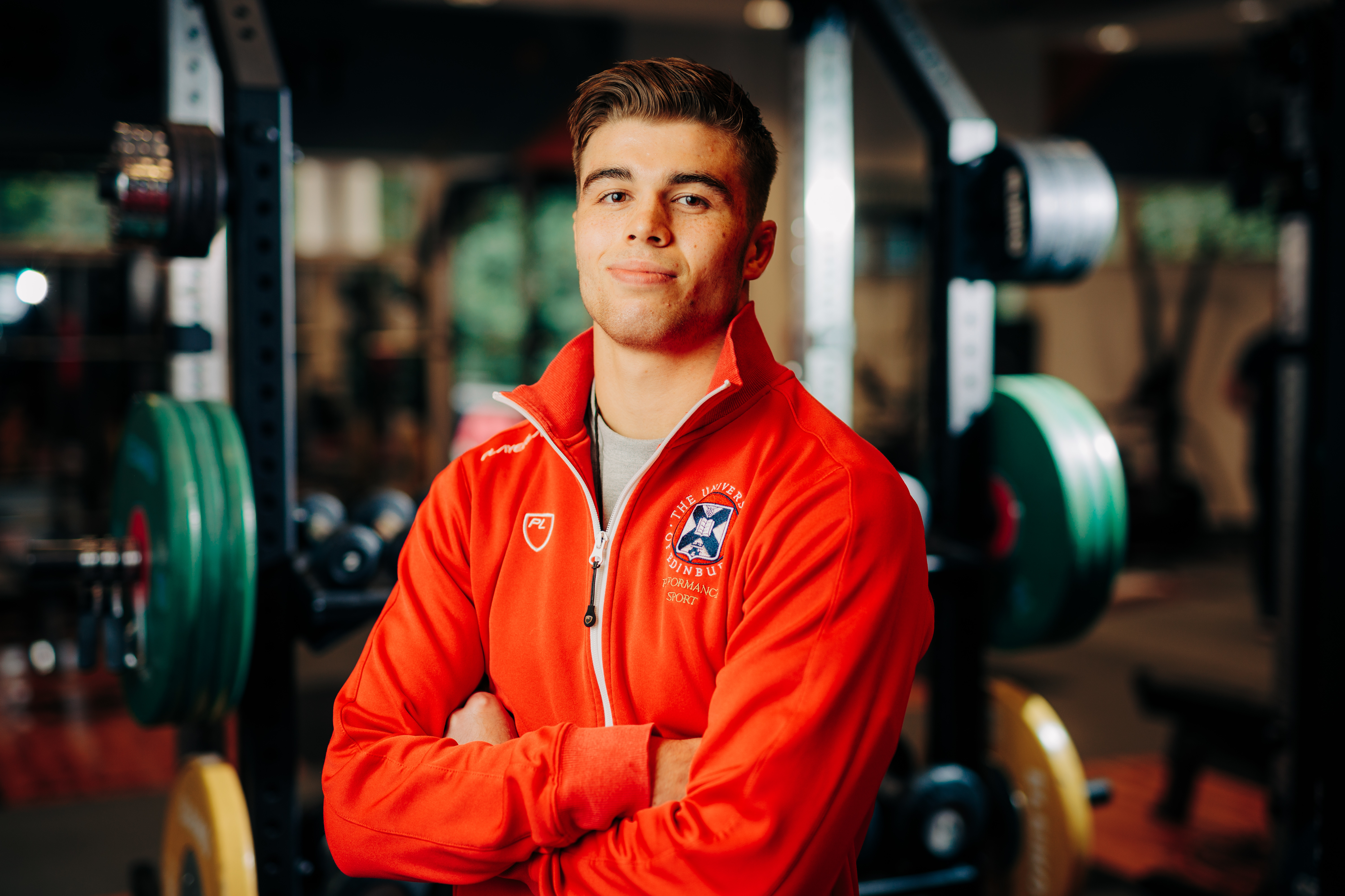 Image of sport scholar Oliver Short smiling with gym in background