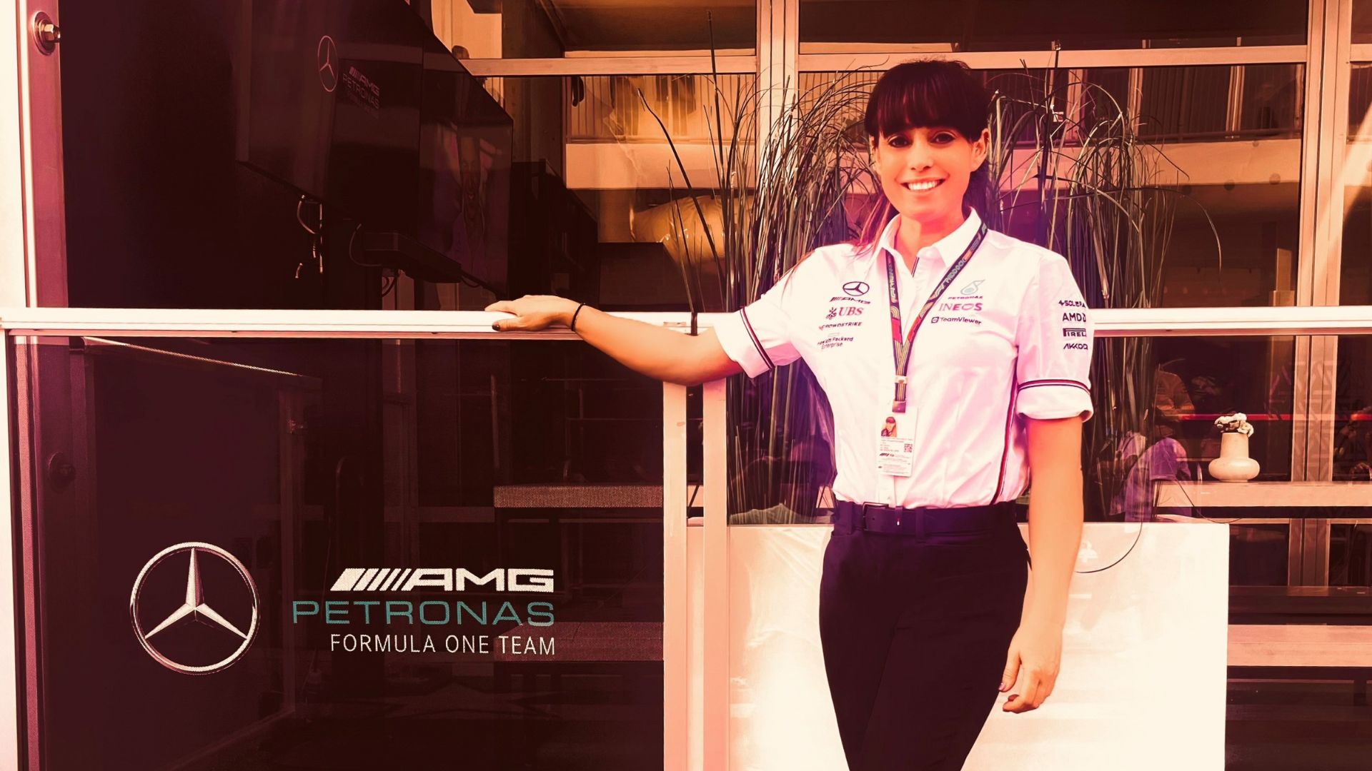 Tracy McAdam smiling next to the AGM Petronas Formula 1 Mercedes team sign in mercedes uniform 
